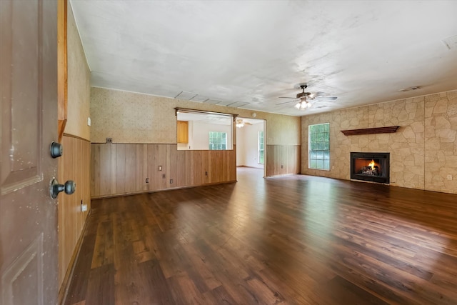 unfurnished living room featuring a fireplace, ceiling fan, and dark hardwood / wood-style flooring