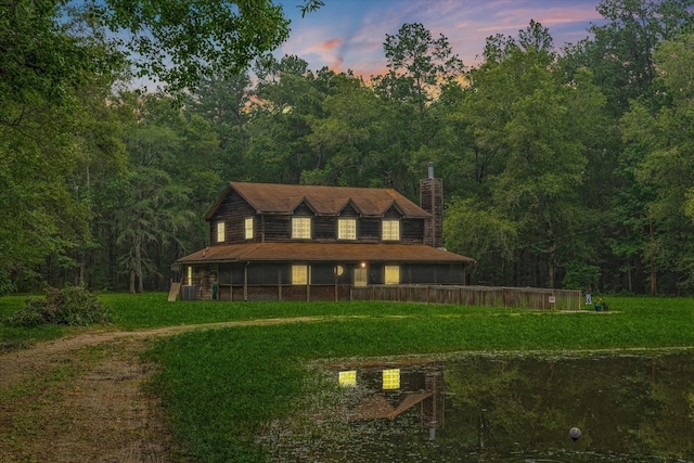 back house at dusk featuring a lawn