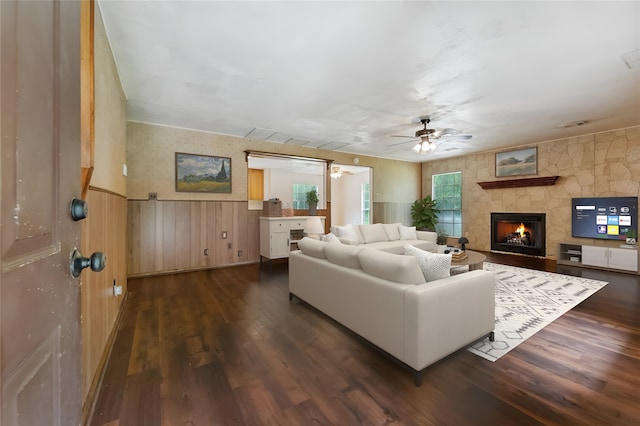 living room featuring dark wood-type flooring, ceiling fan, and a fireplace