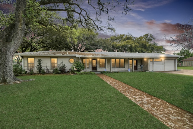 ranch-style house featuring a garage and a lawn