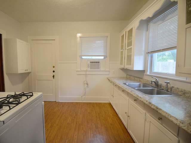 kitchen with white cabinets, sink, light hardwood / wood-style floors, and stove