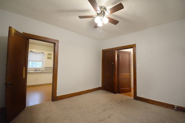 carpeted empty room featuring a textured ceiling, sink, and ceiling fan