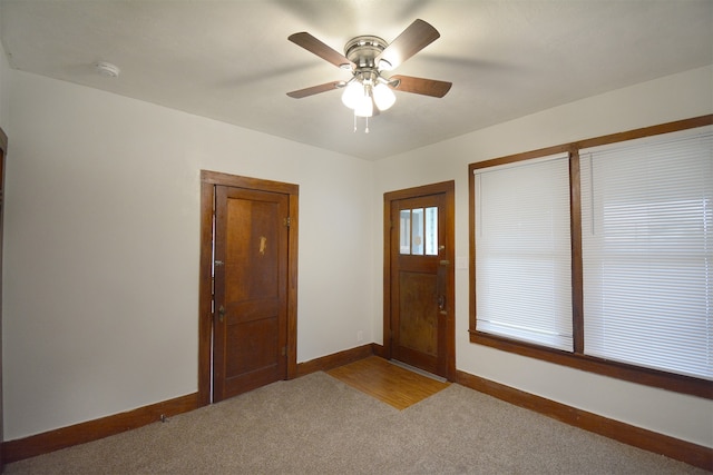 entrance foyer with ceiling fan and carpet