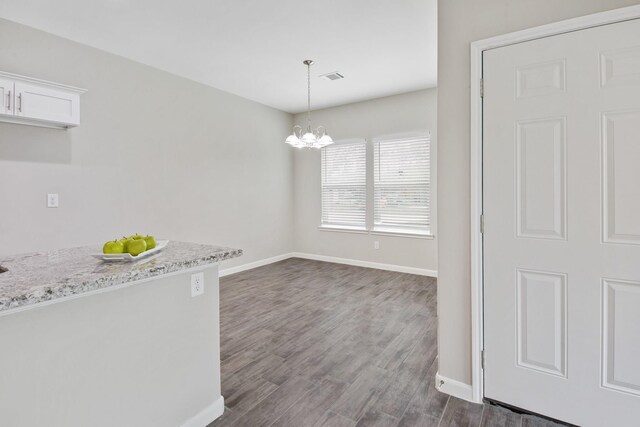 unfurnished dining area with a chandelier and dark wood-type flooring