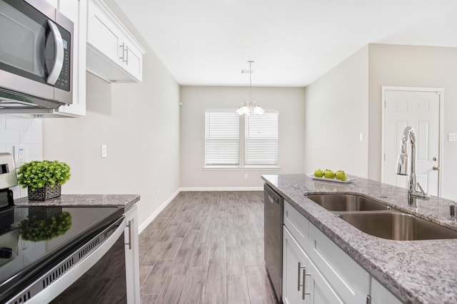 kitchen with light wood-type flooring, stainless steel appliances, sink, white cabinets, and a chandelier