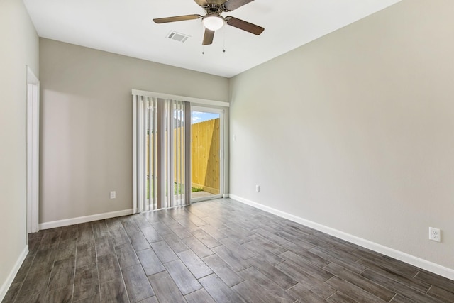 spare room with a ceiling fan, visible vents, dark wood finished floors, and baseboards