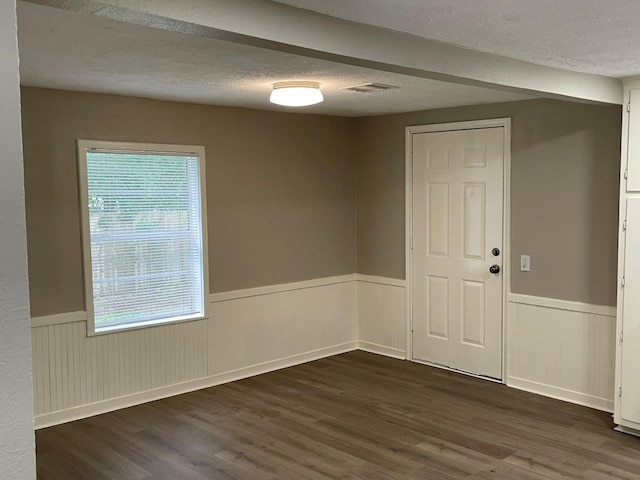 spare room featuring a textured ceiling and dark hardwood / wood-style floors