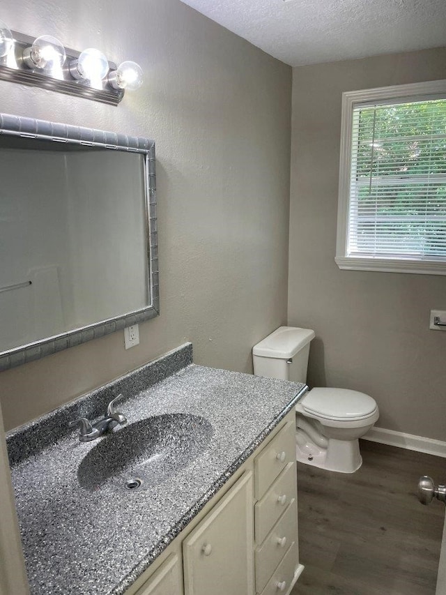 bathroom featuring a textured ceiling, wood-type flooring, vanity, and toilet