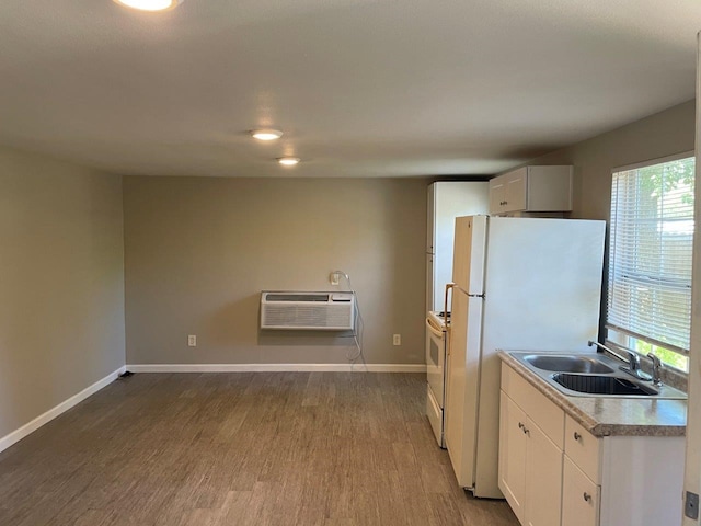 kitchen with sink, hardwood / wood-style floors, white appliances, white cabinetry, and a wall mounted air conditioner