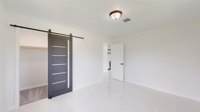 unfurnished bedroom featuring tile flooring, a barn door, and a closet