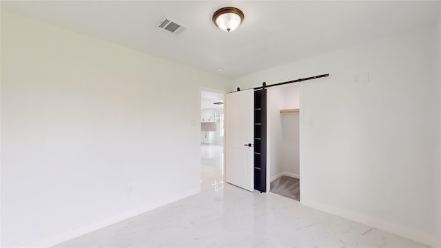 spare room featuring a barn door and light tile floors