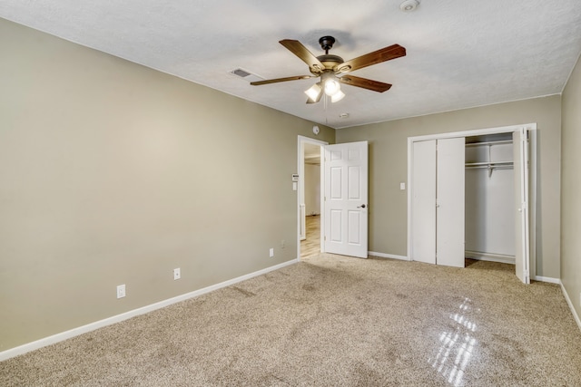 unfurnished bedroom featuring a closet, ceiling fan, a textured ceiling, and light colored carpet