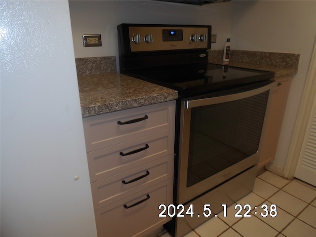 kitchen with white cabinetry, stainless steel electric stove, and light tile flooring