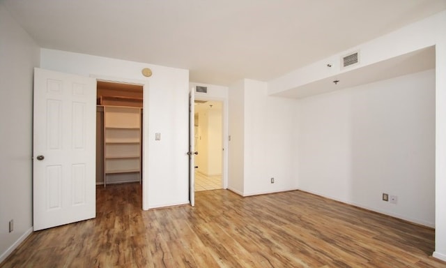 unfurnished bedroom featuring a walk in closet, a closet, and tile floors