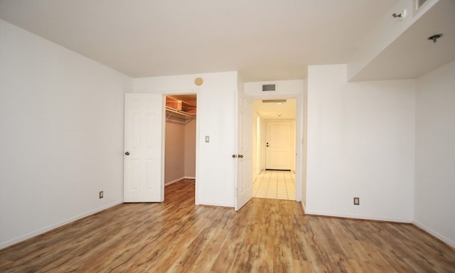 unfurnished bedroom featuring a closet, hardwood / wood-style flooring, and a spacious closet