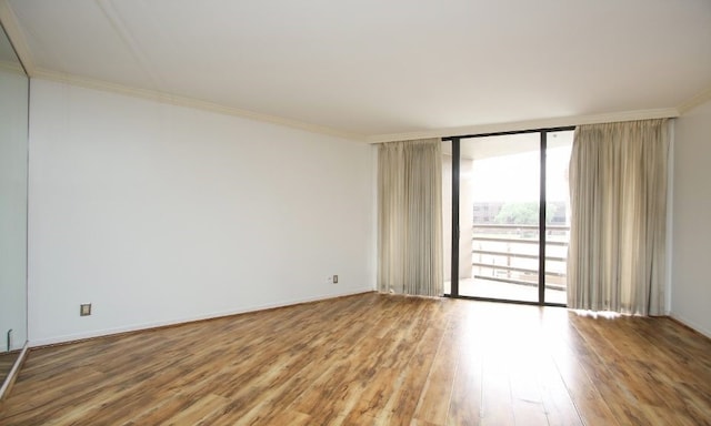 empty room with floor to ceiling windows, ornamental molding, and hardwood / wood-style floors