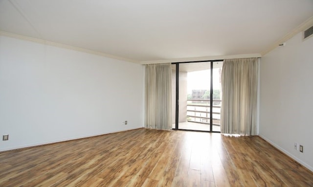 empty room with ornamental molding, a wall of windows, and hardwood / wood-style flooring