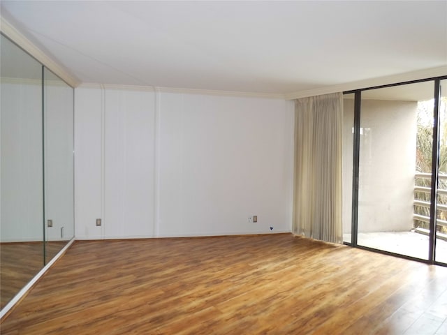 spare room featuring a wealth of natural light, hardwood / wood-style flooring, and a wall of windows