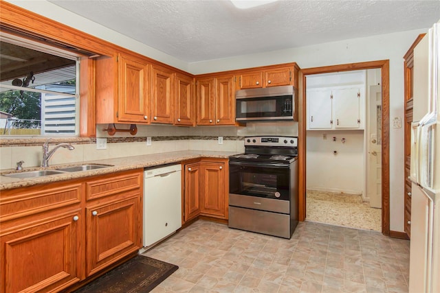 kitchen with decorative backsplash, a textured ceiling, appliances with stainless steel finishes, and sink