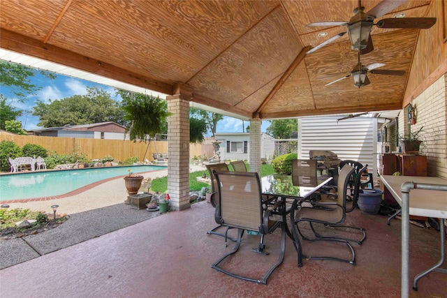 view of patio with ceiling fan, a fenced in pool, and a storage unit