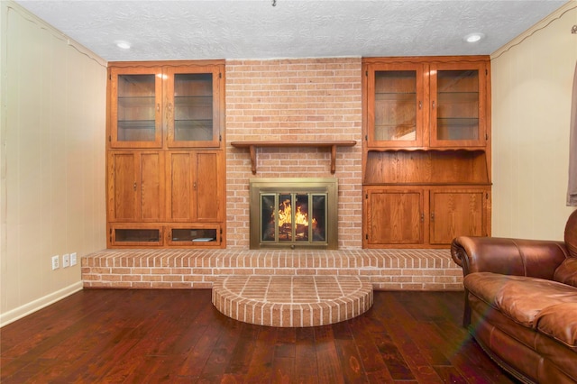 living room featuring a textured ceiling, wood-type flooring, and a brick fireplace