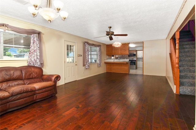 living room with ceiling fan with notable chandelier, a textured ceiling, and dark hardwood / wood-style floors