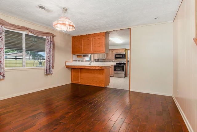 kitchen with a textured ceiling, kitchen peninsula, dark wood-type flooring, and stainless steel appliances