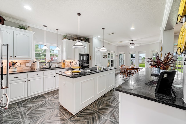 kitchen featuring a textured ceiling, a kitchen island, backsplash, and white cabinets