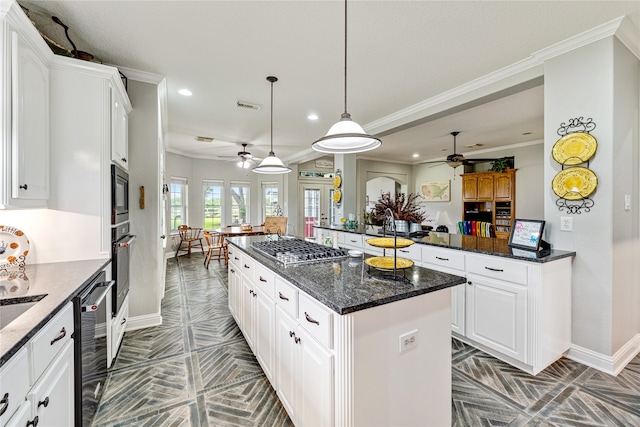 kitchen with hanging light fixtures, a kitchen island, white cabinetry, stainless steel appliances, and dark stone countertops