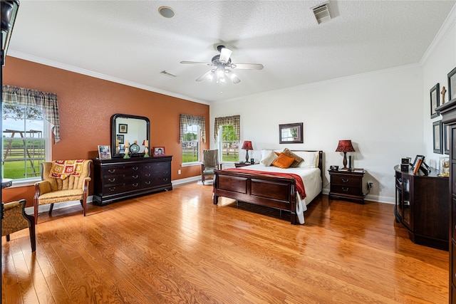 bedroom with a textured ceiling, crown molding, ceiling fan, and light hardwood / wood-style flooring