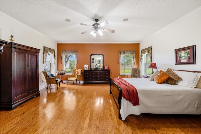 bedroom featuring ceiling fan, a textured ceiling, light hardwood / wood-style flooring, and crown molding