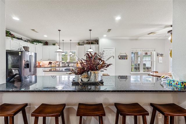 kitchen with white cabinets, kitchen peninsula, dark stone counters, high end refrigerator, and a textured ceiling