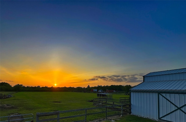 yard at dusk with a rural view and a storage shed