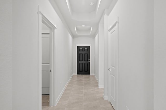 hall featuring a raised ceiling and light tile patterned flooring