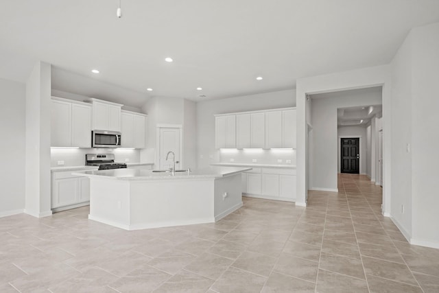 kitchen featuring white cabinets, sink, light tile patterned floors, an island with sink, and appliances with stainless steel finishes