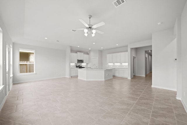 unfurnished living room with ceiling fan, sink, and light tile patterned floors