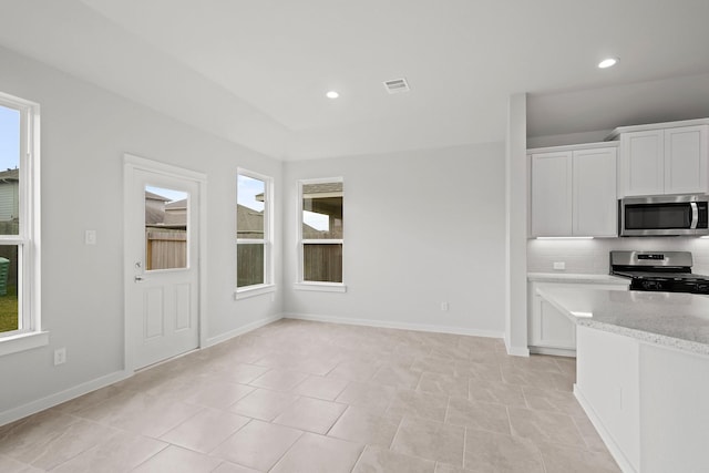 kitchen featuring light stone counters, white cabinets, a healthy amount of sunlight, and appliances with stainless steel finishes