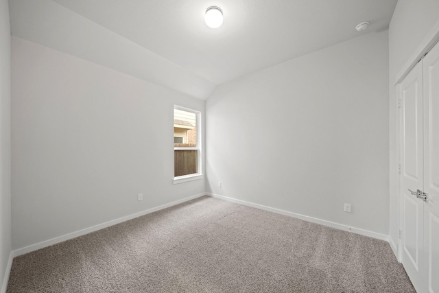 carpeted spare room with vaulted ceiling