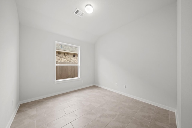 unfurnished room with light tile patterned flooring and vaulted ceiling