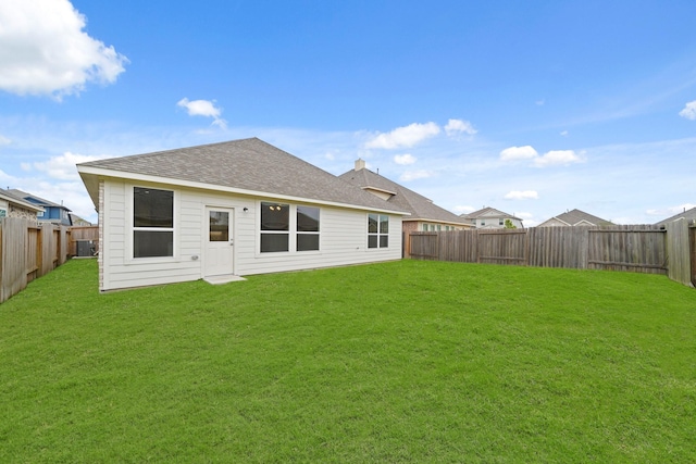 rear view of house with central air condition unit and a yard