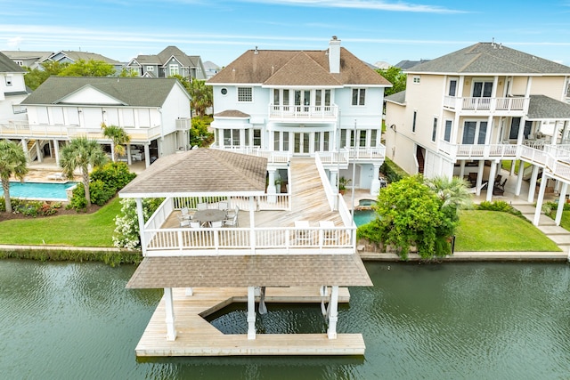 dock area with a pool side deck with water view, a balcony, and a lawn