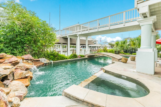 view of pool featuring pool water feature and an in ground hot tub