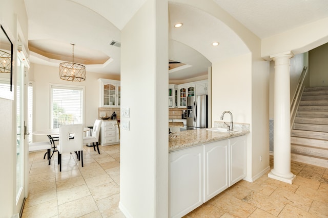 bar with white cabinets, stainless steel refrigerator with ice dispenser, and a tray ceiling