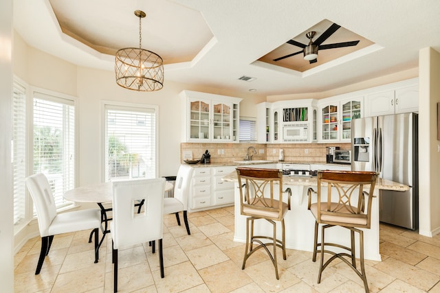 kitchen with tasteful backsplash, white cabinetry, a kitchen island, and a tray ceiling