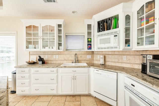 kitchen with white cabinets, white appliances, light tile floors, sink, and tasteful backsplash