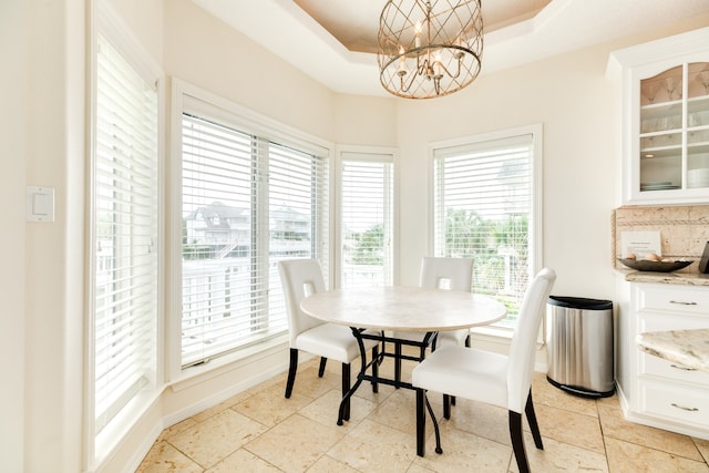 tiled dining room featuring a notable chandelier and a raised ceiling