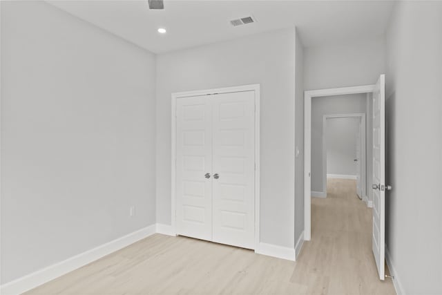 unfurnished bedroom with light hardwood / wood-style flooring and a closet