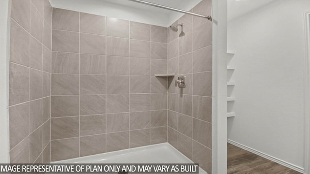 bathroom with tiled shower and wood-type flooring