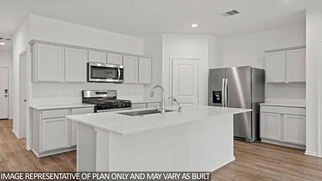 kitchen featuring sink, gray cabinets, an island with sink, light hardwood / wood-style floors, and stainless steel appliances