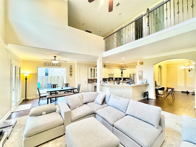 living room with ceiling fan with notable chandelier, a high ceiling, and hardwood / wood-style flooring